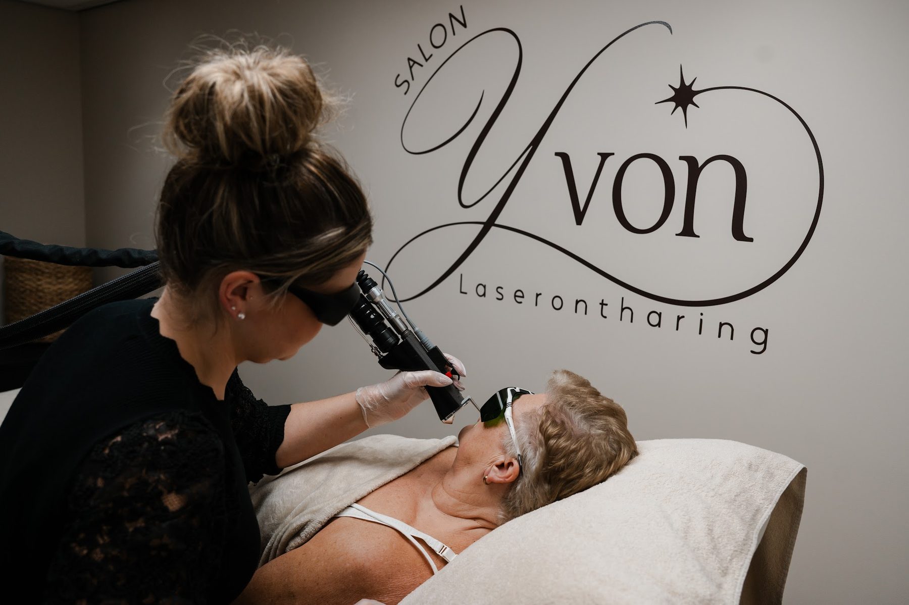 Yvonne behandelt de bovenlip van een klant met de laser, beiden met een beschermbril